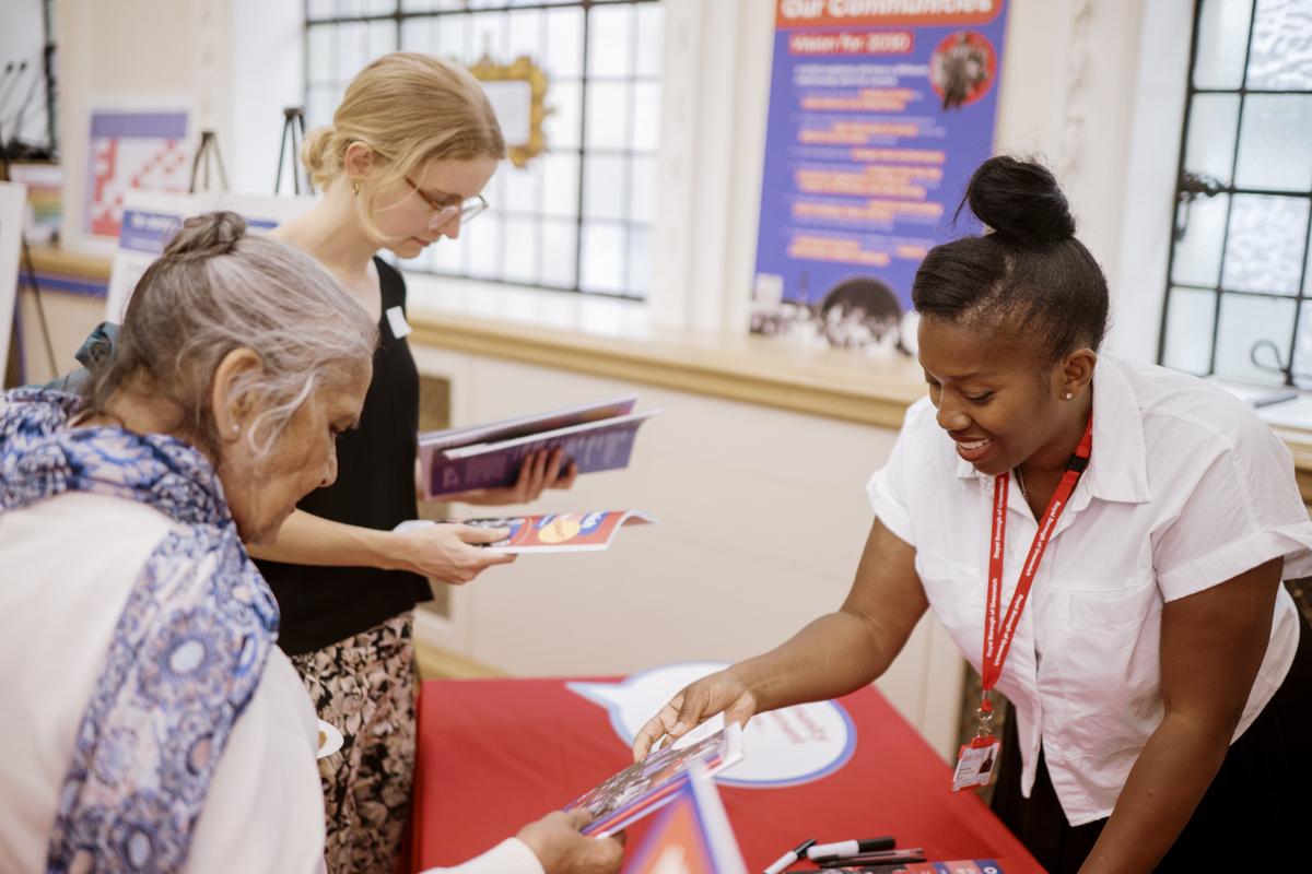 Three women around a table looking at paper documents