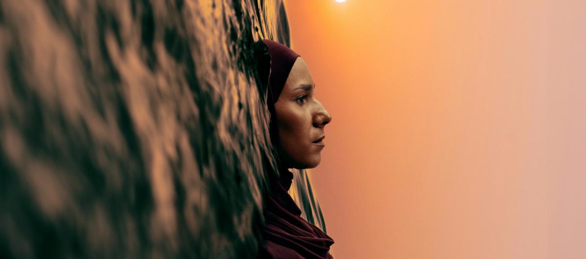 Vertical image of a woman floating in water under a sunset sky.