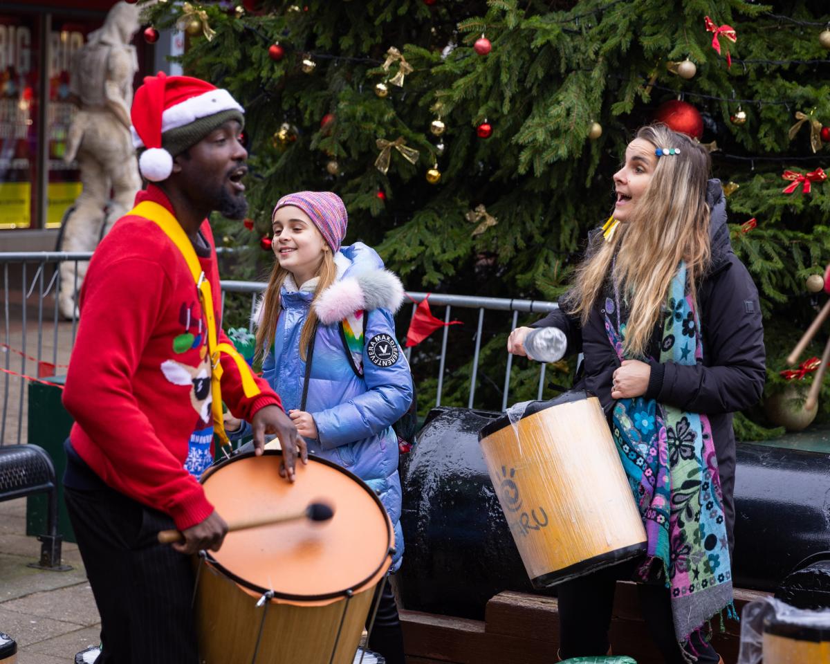 Three people playing drums in festive clothing