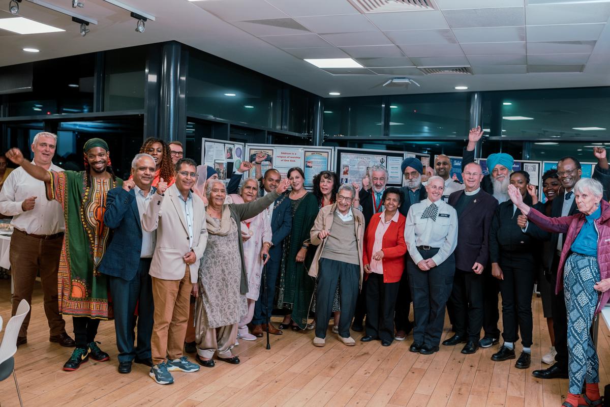 Mayor of the Royal Borough of Greenwich Councillor Jit Ranabhat with community members and local faith leaders posing in front of a display with information about different denominations.