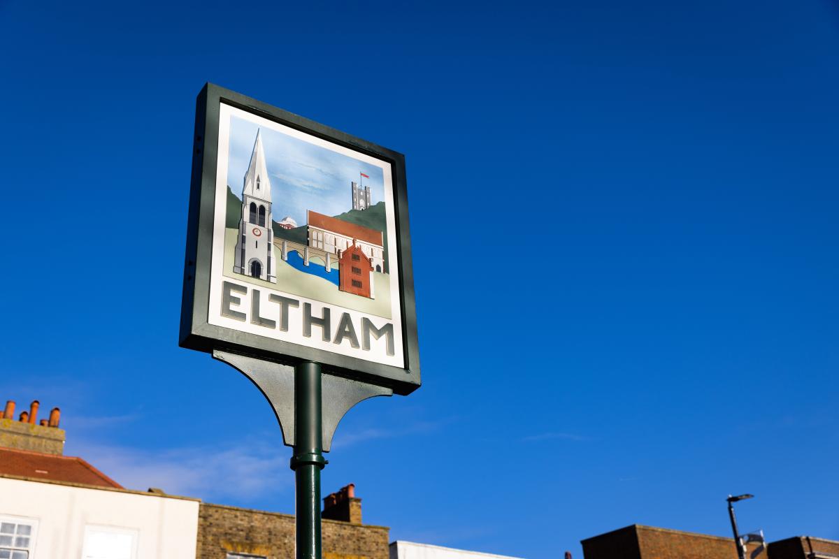 Sign with an illustration of Eltham and bold black text reading "ELTHAM" in front of a blue sky