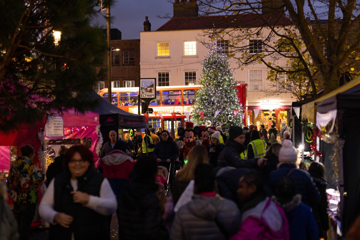 A crowd of people in a market in front of a Christmas tree