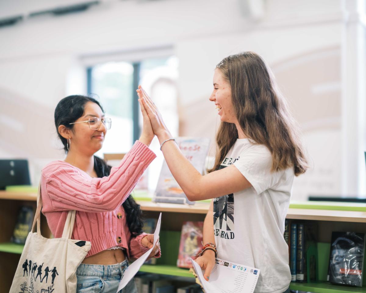 Two people high fiving with their results in hand