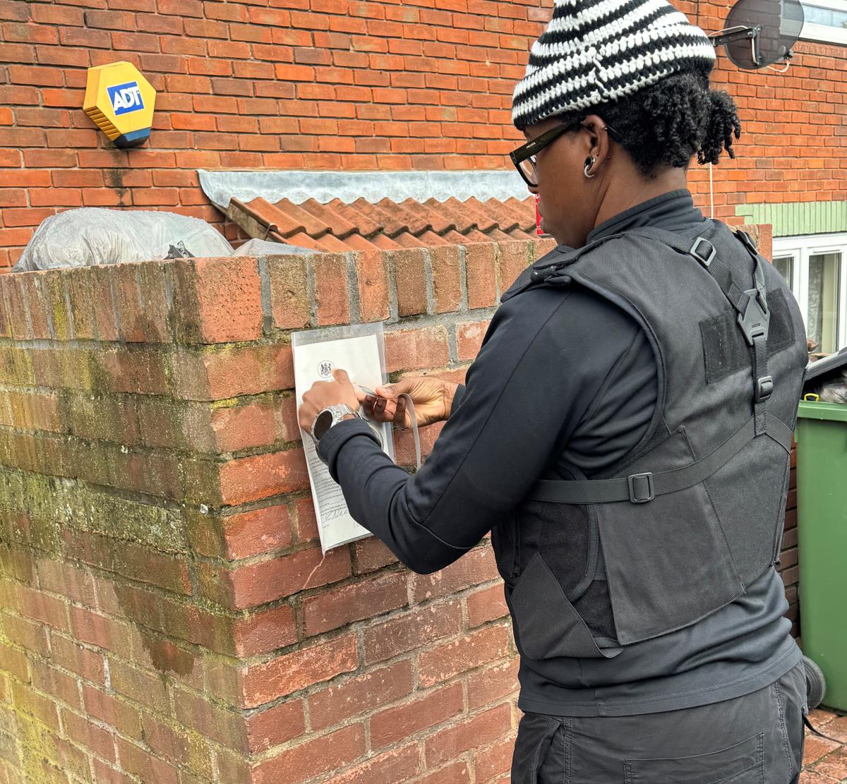 A photo of an enforcement officer putting up a closure notice on a property.