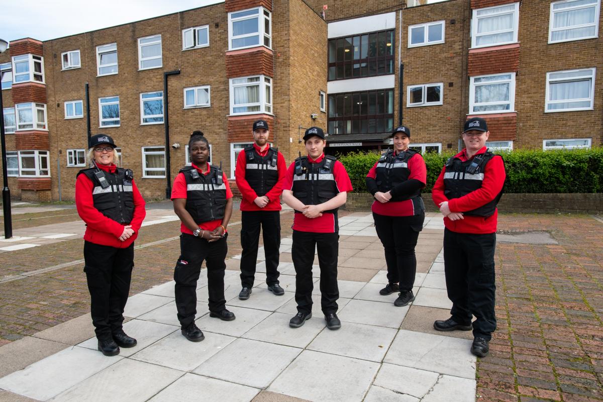 A photo of 6 Community Safety Enforcement Officers standing in front of some flats.