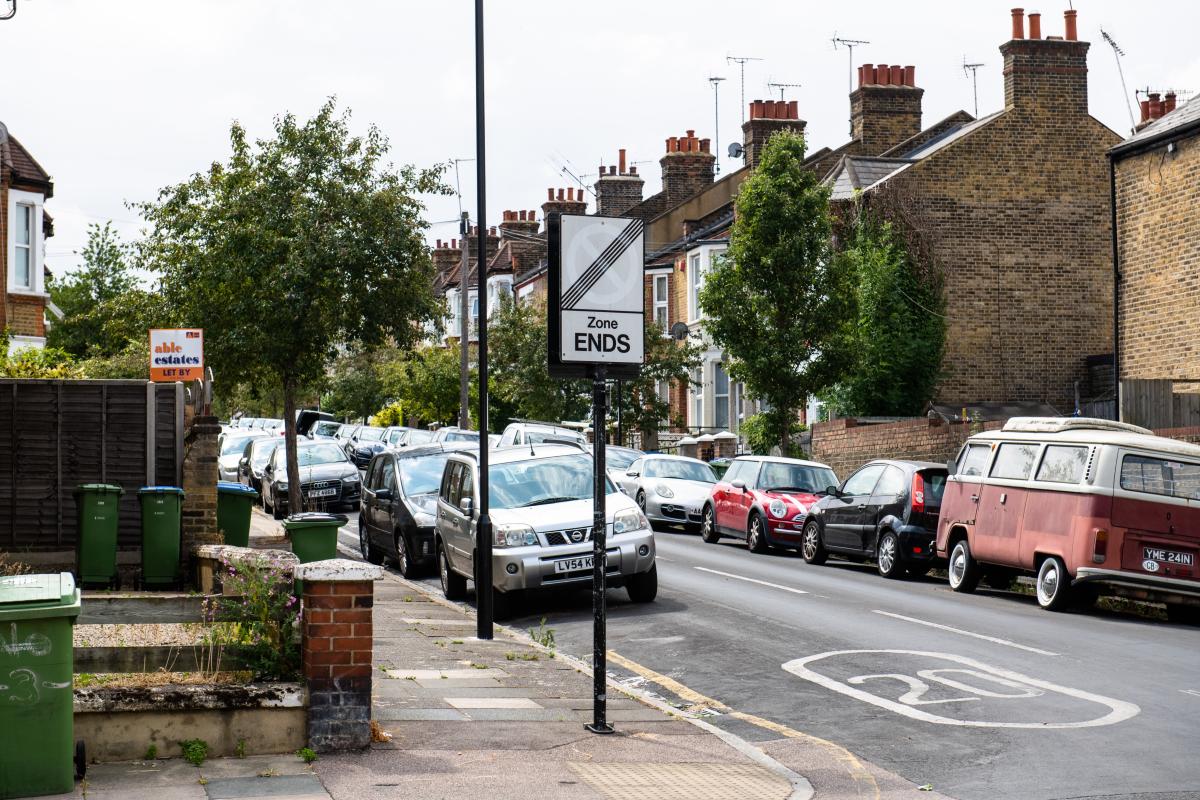 A photo of a road with parked cars lined either side.