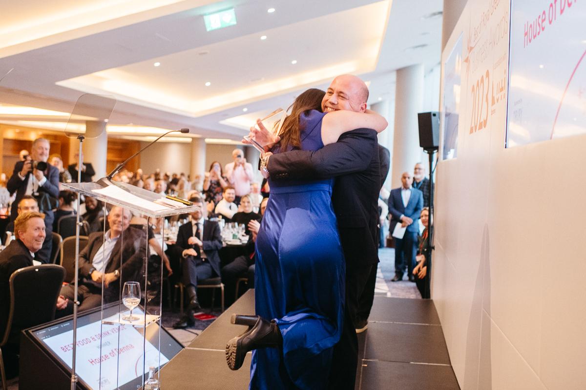 Man hugging woman on stage at the Best of Royal Greenwich Business Awards 2023