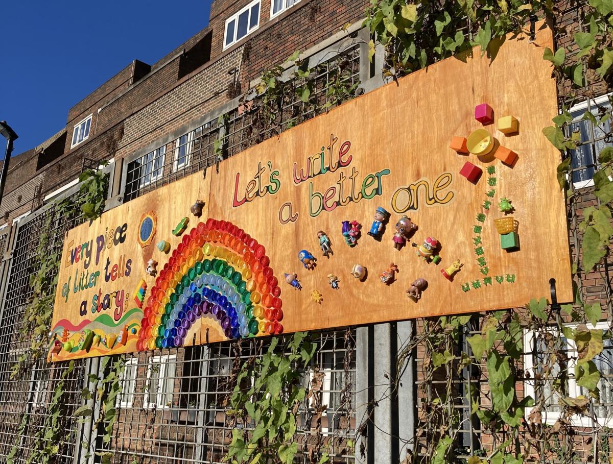 A photo of a mural installed on a gate. The text reads: Every piece of litter tells a story. Let's write a better one.