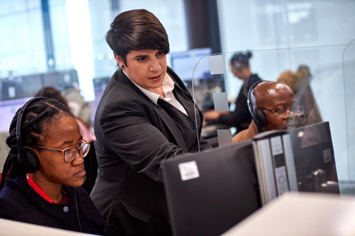 Member of staff supporting another while looking at a screen