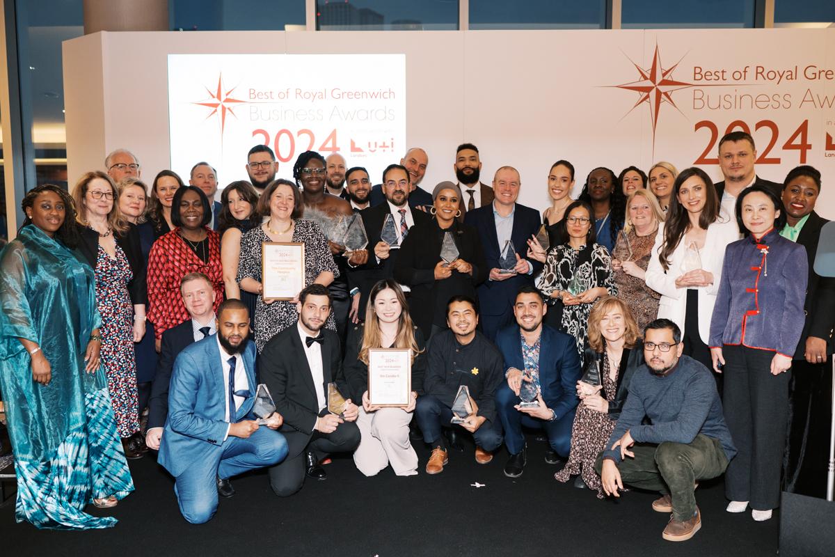 All the Business Awards winners on stage smiling and holding glass trophies