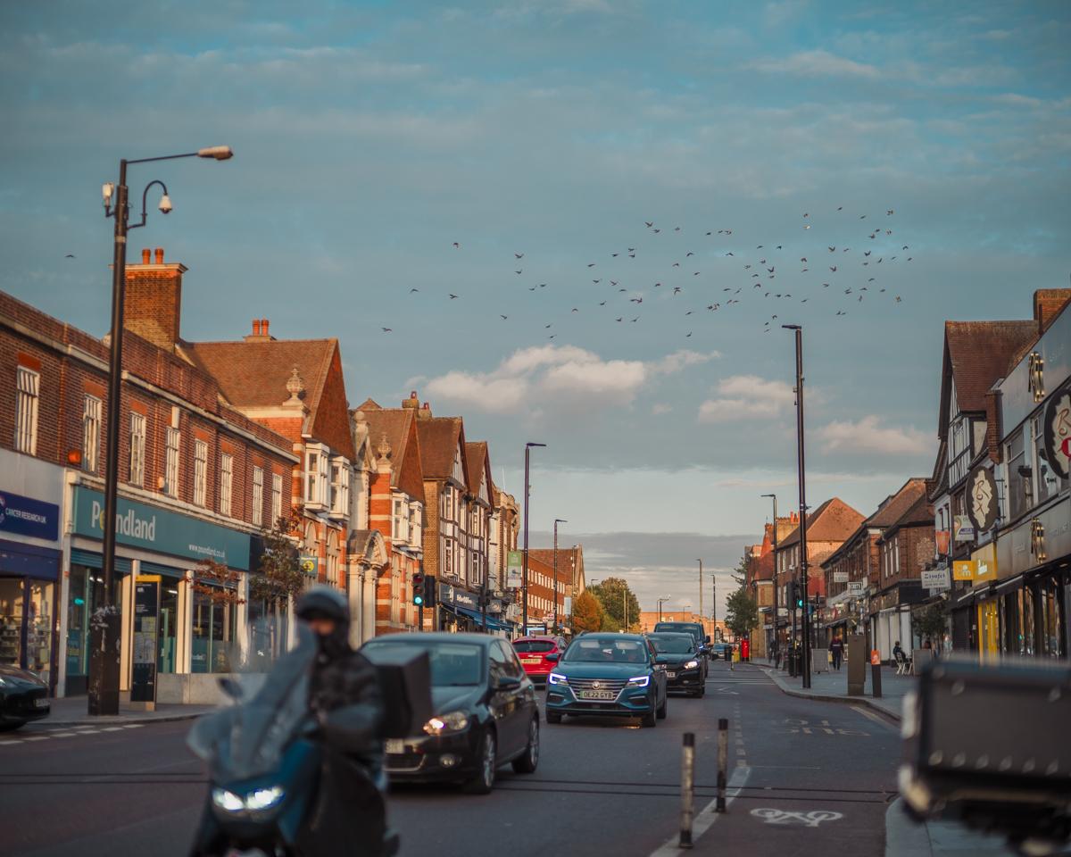 Landscape shot of Eltham high street with cars and motorbikes driving in the road