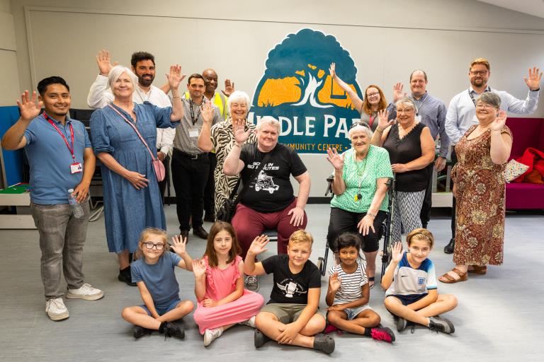 Councillors, council staff, centre users and contractors waving in front of the Middle Park Community Centre logo.