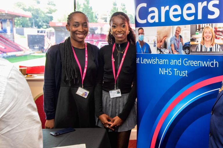 Two people smiling next to a pop-up banner that says 'Careers' at Lewisham and Greenwich NHS Trust