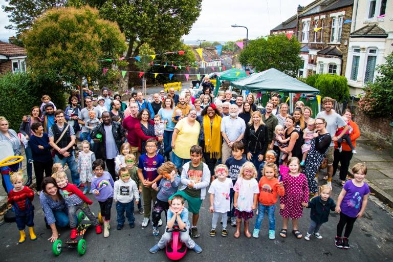 Large group of residents standing on a closed street under colourful bunting.