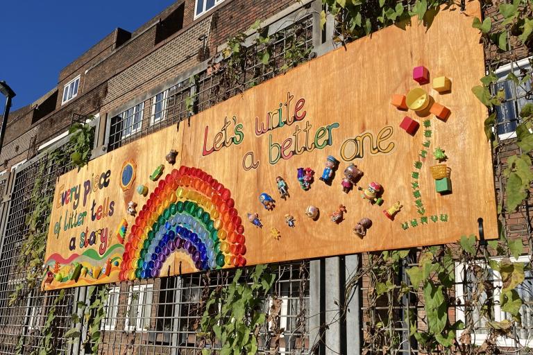 A photo of a mural installed on a gate. The text reads: Every piece of litter tells a story. Let's write a better one.