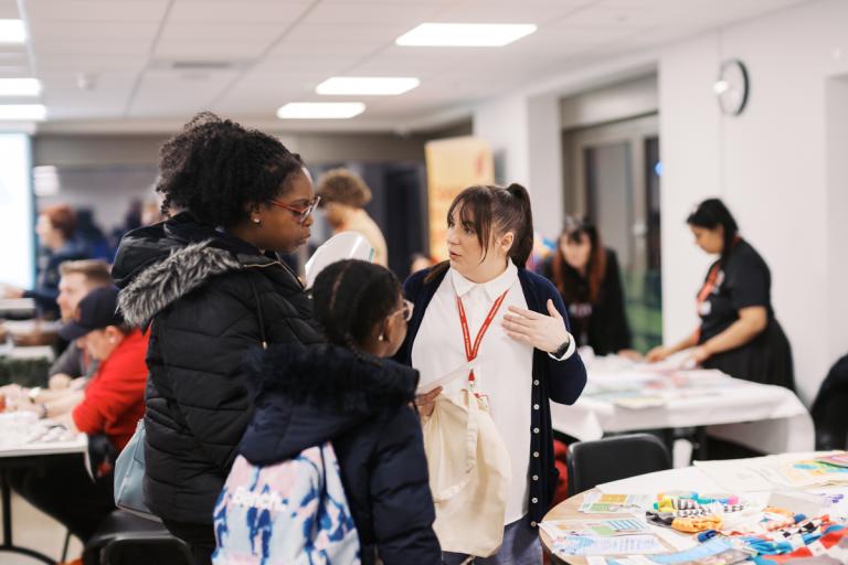 a woman and her daughter talking to a member of staff