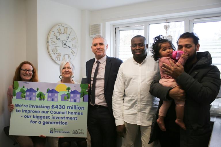 Council leader and Cllrs Taggart-Ryan and Cllr Slattery holding  a sign that reads: 'We're investing £430 to improve our council homes - our biggest investment for a generation' with Andre Culleton standing in a newly renovated kitchen with a resident and his young child