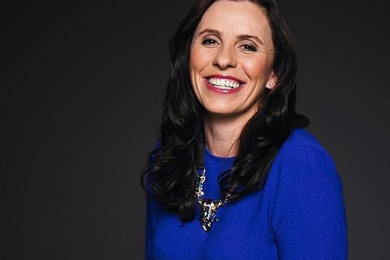 Publicity shot of Even Daniels. She is faced to camera, smiling and wearing a blue top