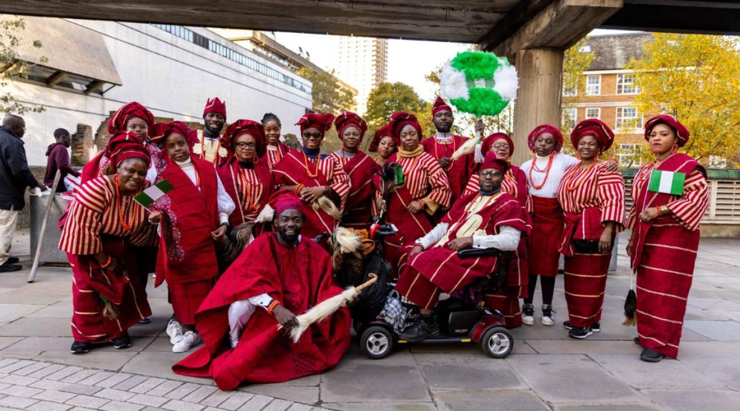Image taken from Mayor's show parade, showing people dressed in traditional red outfits, some holding Nigerian flags.