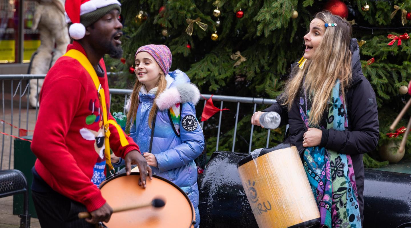 Three people playing drums in festive clothing