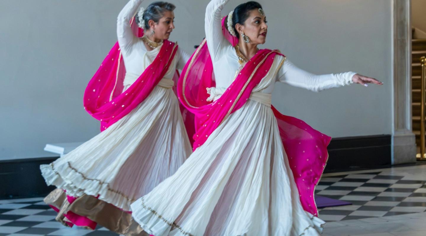 Two women in white and pink lehengas dancing